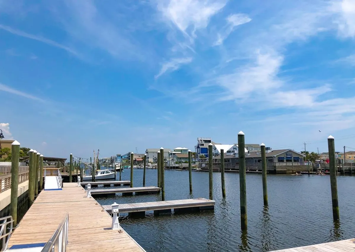 A waterfront scene featuring a wooden dock, boats, and calm water surrounded by houses. This image suggests access to the Intracoastal Waterway, inviting guests and their pets to explore beyond the property—whether strolling the docks, watching boats, or enjoying the surrounding natural beauty.