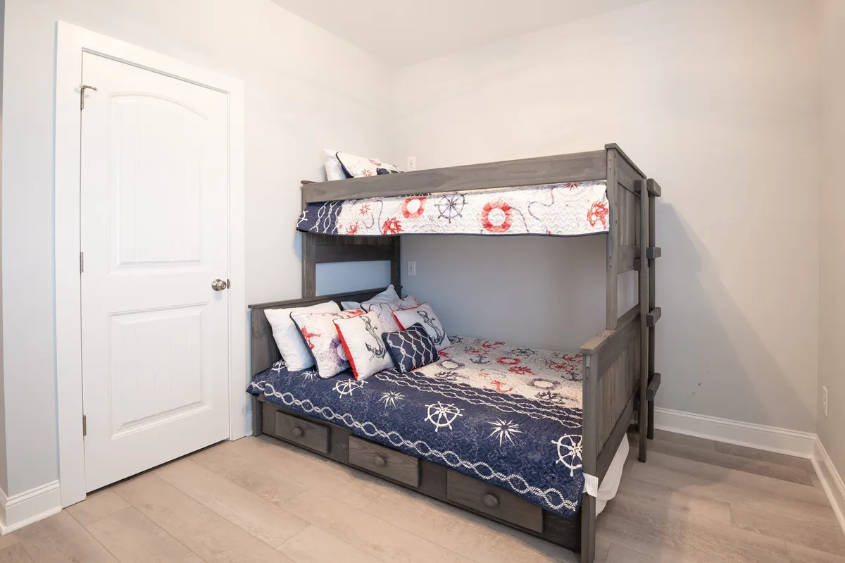 A playful bunk room with a nautical theme, showcasing a sturdy bunk bed, decorative pillows, and cheerful bedding. The space is cozy and clearly designed with children or younger guests in mind, echoing the section's mention of a bunk room ideal for kids or cousins.