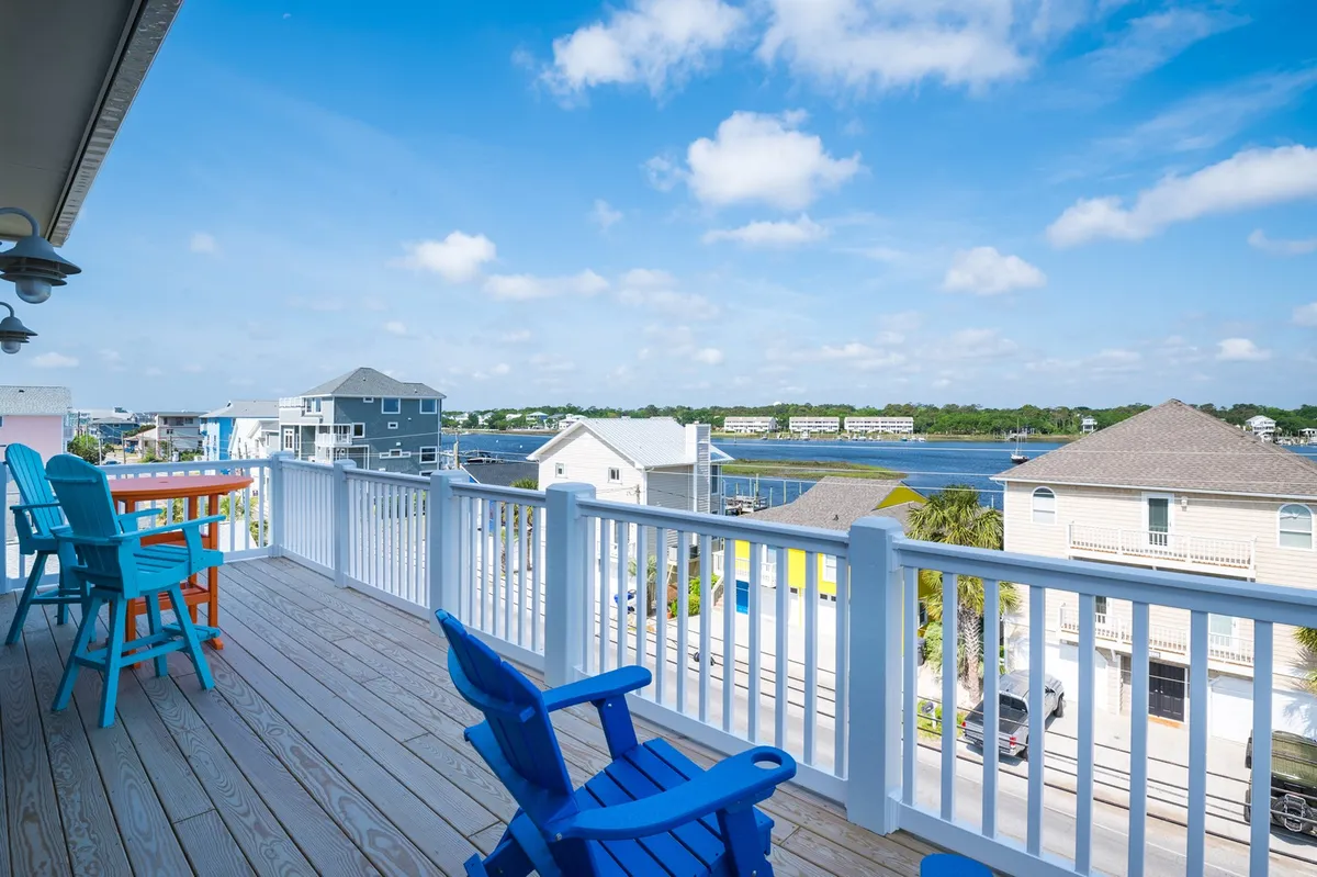This image features colorful outdoor furniture arranged on a deck with a serene view of the water and a bright blue sky overhead. The scene radiates a cheerful and inviting atmosphere, perfect for relaxing or gathering after a day of outdoor adventure.