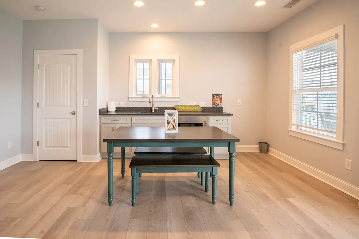 This image showcases the main kitchen area, with a prominent kitchen island, dining table, and large windows letting in natural light. The welcoming atmosphere is perfect for highlighting the home's central gathering and cooking space.