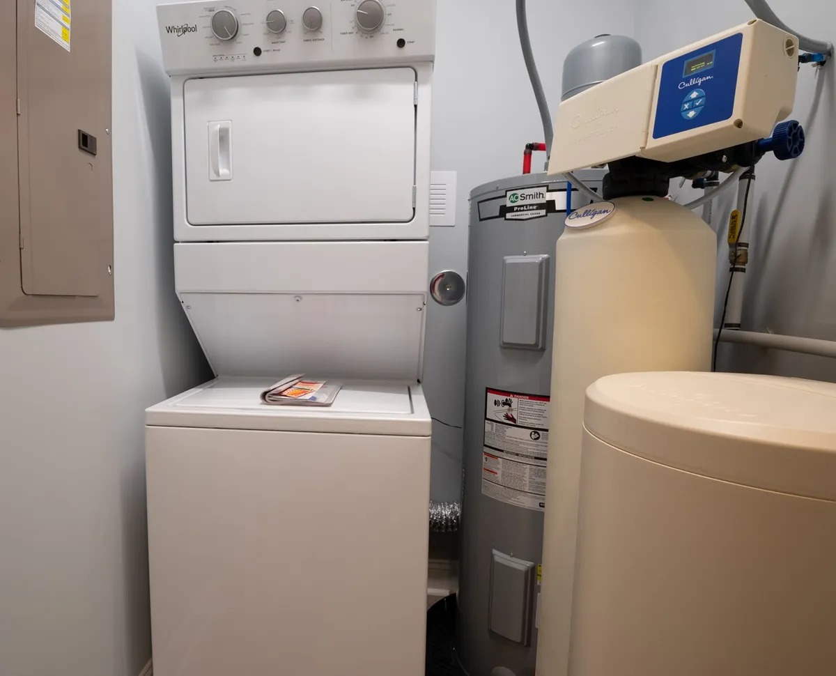 A functional laundry area with a washer and dryer, water heater, and filtration system, situated for easy access and efficiency. The area is tidy and practical, supporting the comfort and convenience advertised.